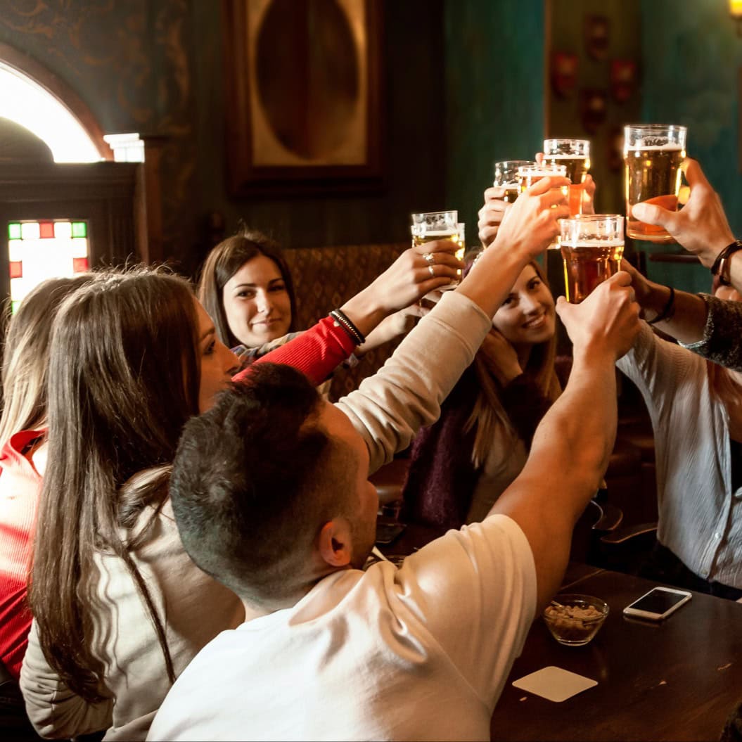 Gruppe von Menschen, die in einer Kneipe feiern und Bier trinken